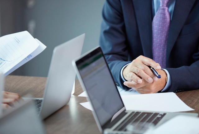 スーツ姿の担当者が資料とノートPCを前に特定技能の登録支援業務について打ち合わせをしている様子