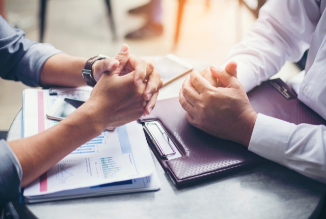 書類と資料を前に面談するビジネス担当者。雇用や支援内容の相談場面を示すイメージ写真