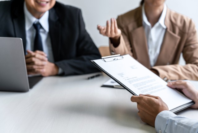 書類を確認しながら採用面接を行うビジネス担当者。雇用や人材選考に関する相談の場面を示すイメージ