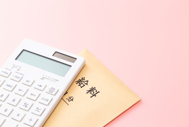 給与封筒と電卓が置かれた写真。給料計算や賃金管理、支払いに関する内容を示すイメージ。