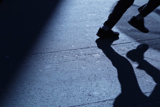 失踪者の影 特定技能外国人の失踪問題を示唆する、暗い路上を歩く人物の足元と影のイメージ写真