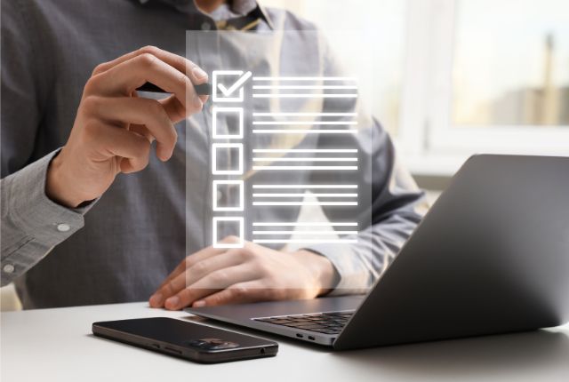 法令遵守のチェックリスト ノートパソコン前でチェックリストを操作する人物の写真。業務手続きや確認作業をイメージしたビジネスシーン。