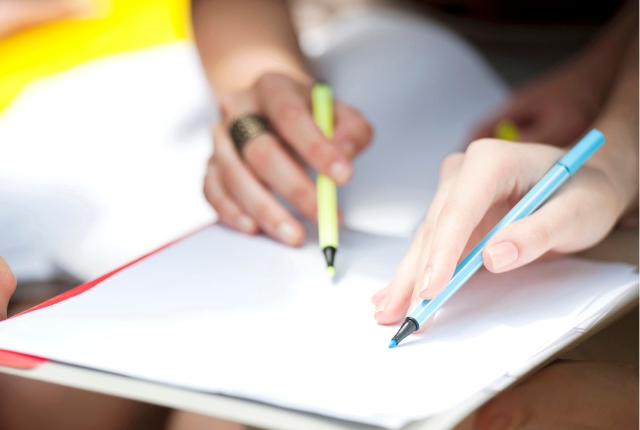 2人が紙にペンで書き込む様子。給与の説明をイメージした写真。
