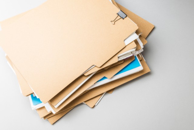 MWO申請書類の準備 書類が入ったファイルの山。MWO申請やフィリピン人雇用に必要な提出書類をイメージした画像。