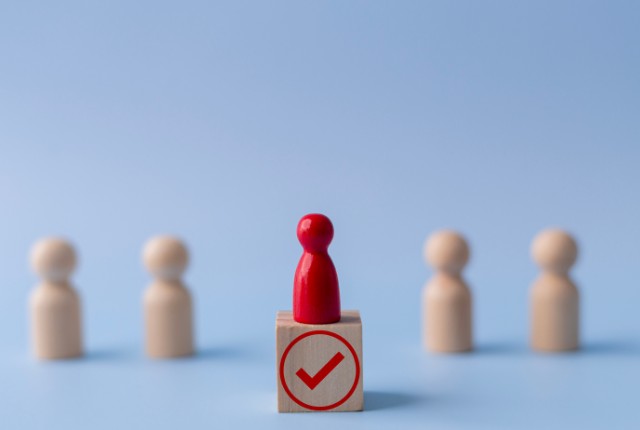 採用や選考を象徴する赤い駒とチェックマークのブロック。相談窓口の選定を表すイメージ