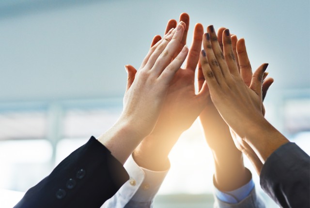 支援体制の成功 複数の手がハイタッチしている写真。チームワークや支援体制の成功を表すイメージ。