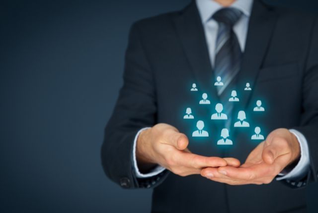 育成就労 スーツの人物が掌に人材アイコンのホログラムを示す画像。外国人材の管理や育成を象徴し、企業の人事戦略を表す。